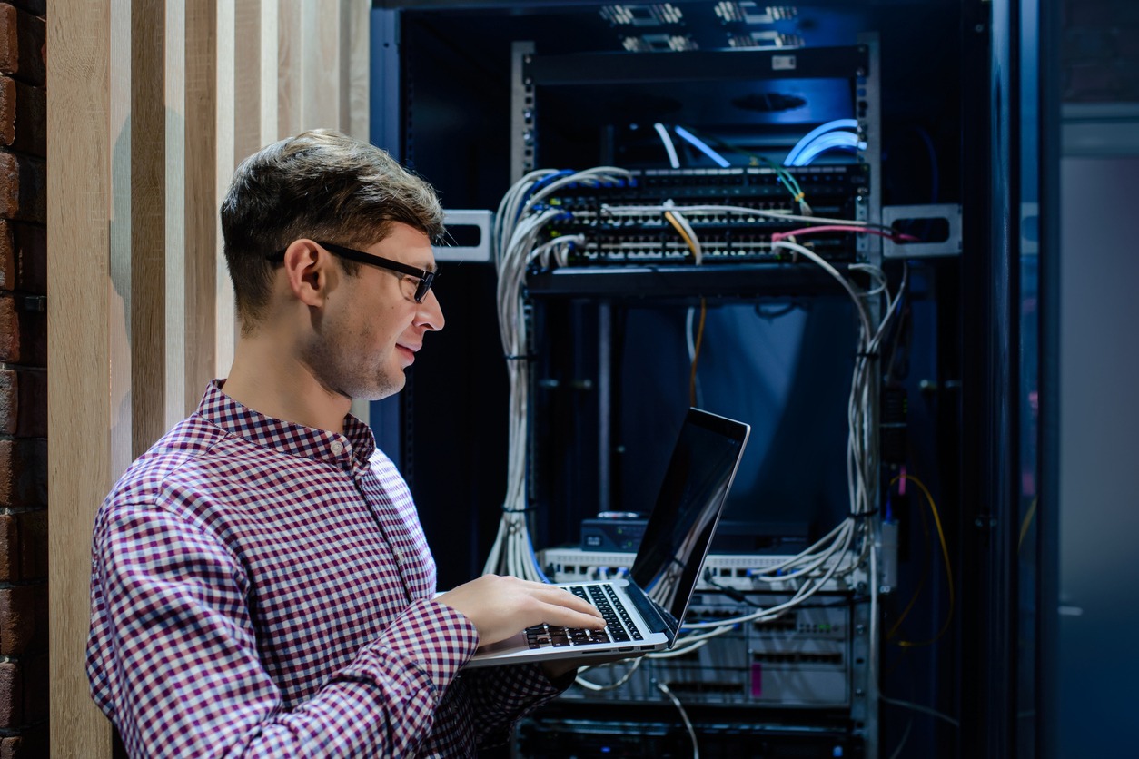 In the server room a technician/ It engineer/ hold the notebook